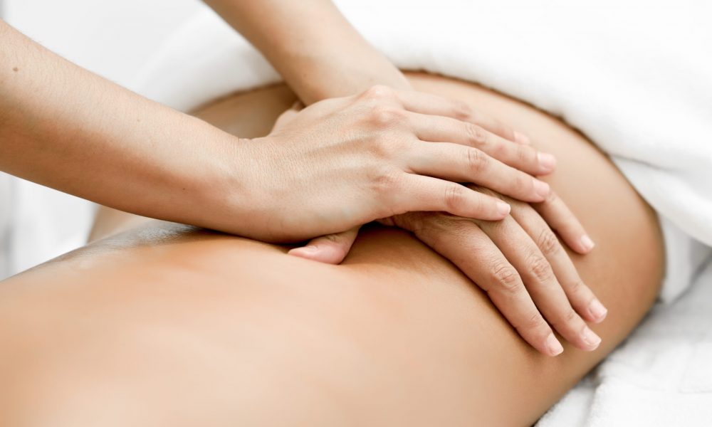 Young woman receiving a back massage in a spa center. Female patient is receiving treatment by professional therapist.